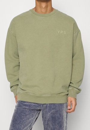 Olijfgroene sweatshirt met een ronde hals, ribgebreide boorden en onderkant, met een subtiel YPS-logo op de borst. Zacht materiaal en een ontspannen fit.