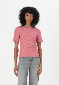Tricou cu dungi roșii și albe, cu mâneci scurte, decolteu rotund și un design ajustat, asortat cu blugi din denim gri.