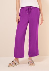 Paarse wijde broek met een trekkoord in de taille, gemaakt van lichtgewicht materiaal. De stof heeft een gladde textuur en een levendige kleur.