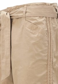 Beżowe spodnie z materiału z wiązanym paskiem, wyposażone w boczne kieszenie i subtelną fakturę. Szwy z przeszyciami wzdłuż bocznych szwów dodają wizualnego uroku.
