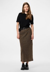 Polo shirt noir à manches courtes associé à une jupe midi en tricot marron côtelé, rehaussé d'une ceinture noire avec une boucle ronde. Porté avec des baskets noires.