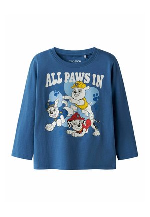 Kék hosszú ujjú gyermek ing, rajta az "ALL PAWS IN" felirat és rajzfilmszerű kölyökkutyák, akik rendőrségi, tűzoltói és építkezési sisakot viselnek.