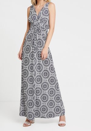 Maxime dress with a black and white circular pattern, sleeveless and featuring a knot detail at the waist, flowing skirt, and smooth fabric.