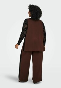 Hnědý tunikový top s černými krajkovými rukávy a odpovídajícími kalhotami. Má široké nohavice, měkkou texturu a boční rozparky.