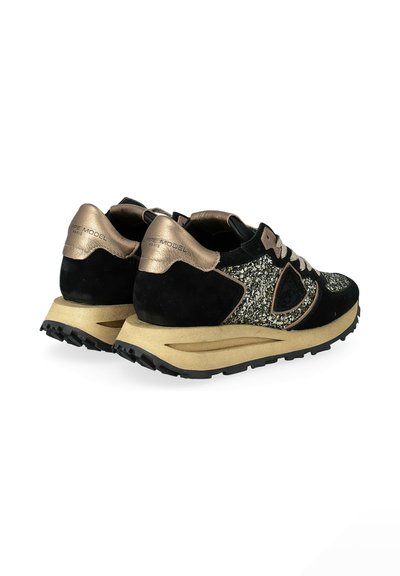 Sports shoes in black suede with gold accents, glittery upper, and thick, textured sole. Features laces and padded collar for support.