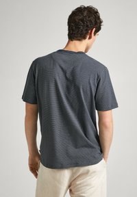 Camiseta de rayas marinas hecha de tela suave, de manga corta, con cuello redondo y corte relajado. Costuras visibles y una ligera textura.