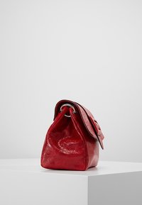 Sac à main en cuir rouge à forme structurée, présentant une texture lisse, une quincaillerie argentée et un rabat à repli.