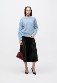 Hele sinise tekstuuriga kampsun, must volditud seelik, burgundi käekott ja mustad terava ninaga kontsad. Lihtne, moodne disain kontrastsete värvidega.