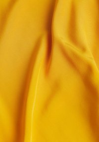 Tissu jaune avec une texture lisse, présentant de subtiles variations de teinte et un doux drapé. Aucun motif ni détail de quincaillerie visible.