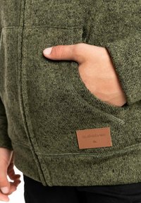 Sudadera con capucha verde de punto con una tela texturizada, bolsillo frontal y una etiqueta de cuero con el logo de 'Quiksilver'.