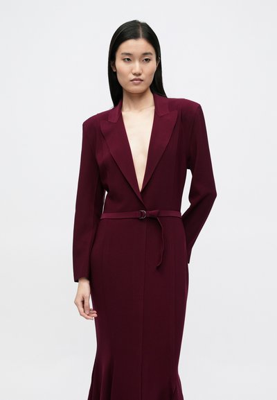 Burgundia pikkade varrukatega kleit sügava dekolteega, vöökohal vöö ja lehviva äärega. Sile tekstuur ja struktureeritud krae detailid.