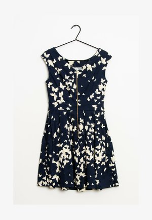 Vestido azul marino sin mangas con patrones de mariposas blancas y cremallera frontal, colgado en una percha negra sobre un fondo blanco.