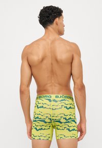 Κίτρινες μποξερές εσώρουχα με πράσινο αφηρημένο σχέδιο και λωρίδα μέσης με το λογότυπο "BJÖRN BORG." Κοντό σχέδιο, ομαλή υφή.