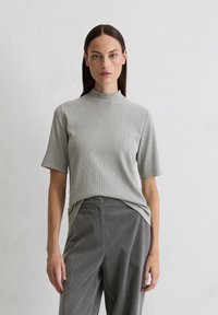 Világosszürke, bordázott, rövid ujjú garbó, laza fit-vel, sötétszürke, magas derekú nadrággal, textúrált anyagból.