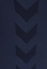 Tissu bleu foncé avec un motif texturé composé de quatre chevrons orientés vers le bas dans une teinte légèrement plus foncée.