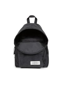 Zaino in corduroy nero con tracolla regolabile, parte superiore arrotondata, chiusura a flap e tasca frontale. Presenta una fodera interna e il logo del brand.