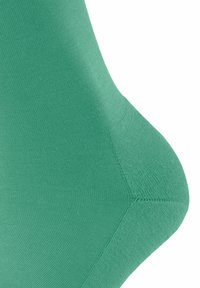 Grüner, strukturierter Stoff mit einer glatten Oberfläche, der ein geformtes Design aufweist. Nahaufnahme betont gerippte Details und Nahtakzente.