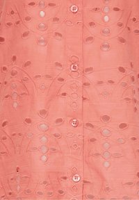 Koralikowy materiał z haftowanym wzorem w kwiaty i czterema małymi dopasowanymi guzikami ułożonymi w pionowym rzędzie.