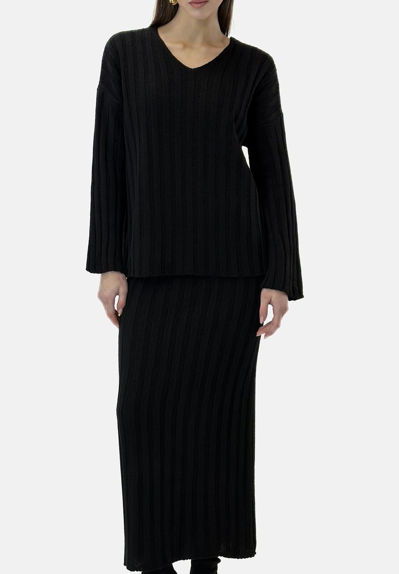 Zwart gebreide outfit met een lange mouw top met V-hals en een bijpassende rok tot op de vloer, beide met een getextureerd geribd patroon.