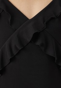 Czarna odzież z dekoltem w serek, wyposażona w warstwowe falbany, wykonana z gładkiego materiału, prezentująca elegancką teksturę i czyste linie.