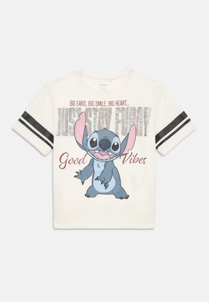 Camiseta blanca de manga corta con rayas negras en las mangas, que presenta al divertido personaje de dibujos animados Stitch sonriendo y el texto "Grandes orejas, gran sonrisa, gran corazón... Solo mantén el humor, buenas vibras."