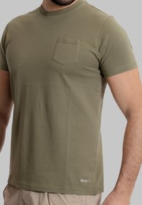 T-shirt a maniche corte verde oliva con taschino sul petto, scollo rotondo e una texture morbida e liscia. Presenta un piccolo logo del marchio sull'orlo.