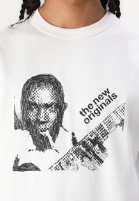 White cotton t-shirt featuring a black sketch of a face and the text “the new originals” in bold font at an angle.