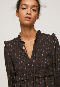 Abito nero con motivo, con arricciature elastiche, colletto e maniche volantrino, caratterizzato da piccoli motivi floreali colorati e un design a orlo a strati.