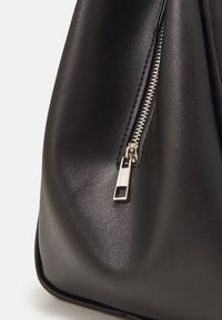 Black leather handbag with a smooth texture, featuring a zippered closure and silver hardware accent on the zipper pull.