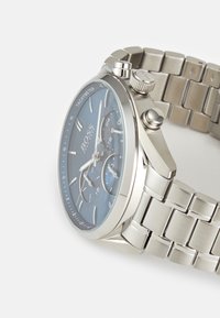 Hõbe roostevabast terasest kell sinise analoogdialli, taksimetri, kronograafi alamdiaalide ja ühendatud käevõru disainiga.