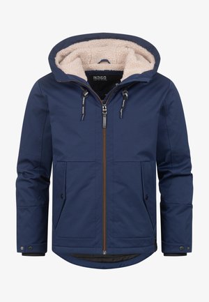 Námořnická modrá zateplená bunda s kapucí podšitou umělou kožešinou, zipem vpředu, dvěma předními kapsami a nastavitelnými šňůrkami. Obsahuje mírně zakřivený lem.