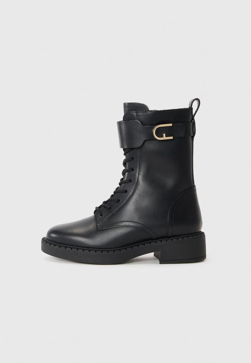 Black leather ankle boot featuring a lace-up front, a rounded toe, a chunky heel, and a decorative strap with a gold buckle accent.