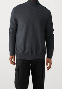 Grå turtleneck-tröja i mjukt material, med långa ärmar och ribbade mudd. Designen är åtsittande med en slät yta.