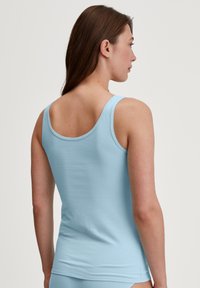 Light blue fitted tank top made of soft cotton, featuring a round neckline and wide straps, with a smooth, seamless back.