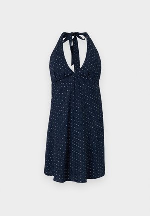 Vestido halter azul-marinho com bolinhas brancas, apresentando um decote profundo, cintura franzida e saia fluida. O tecido tem uma textura suave.