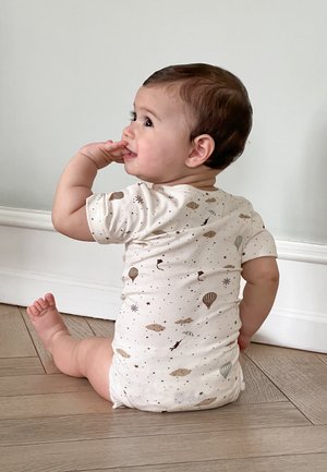 Light beige onesie with short sleeves, featuring colorful patterns of hot air balloons, clouds, and stars. Soft fabric, casual fit.