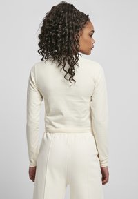 Pitkät hihat crop-top off-white jersey-kangasta. Ominaisuuksiin kuuluu istuva muotoilu, sileä pinta ja pyöreä pääntie.