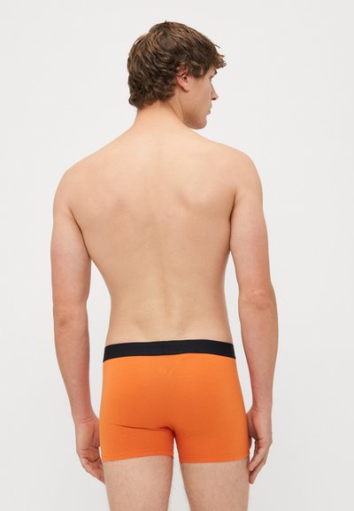 Calções de algodão laranja com um cós elástico preto, apresentando um design ajustado. O tecido parece suave, com costuras mínimas.