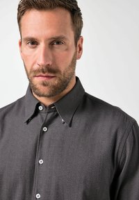 Dunkel gemustertes Hemd mit Kragen, das helle Knöpfe und ein dezentes geometrisches Design aufweist. Glatte Stofftextur.