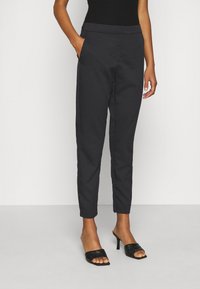 Svarta smala byxor gjorda av ett mjukt tyg. Har sidfickor, en platt midja och en snyggt skräddarsydd passform.