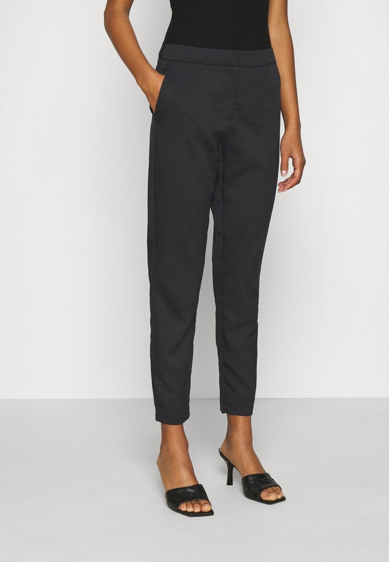 Svarta smala byxor gjorda av ett mjukt tyg. Har sidfickor, en platt midja och en snyggt skräddarsydd passform.