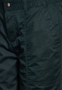 Mörkgröna lätta cargobyxor med en slät yta, featuring en elastisk midja, framfickor och kontrasterande sömdetaljer.