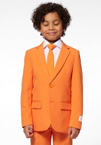 Orange jakkesætjakke med notch-lapel og enkeltknaplukning, parret med et matchende slips og hvid skjorte. Glat stof og tætsiddende pasform.