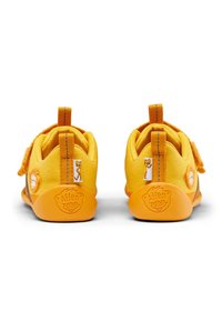Geel peuterschoenen met verstelbare klittenbandsluitingen, een textieloppervlak, oranje zolen en een aaplogo op de hiel. Trekband voor gemakkelijke aan- en uittrek.