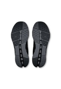 Semelles de chaussures de sport noires avec des motifs texturés, présentant un design segmenté pour une flexibilité et une adhérence accrues. Fabriquées en caoutchouc durable.