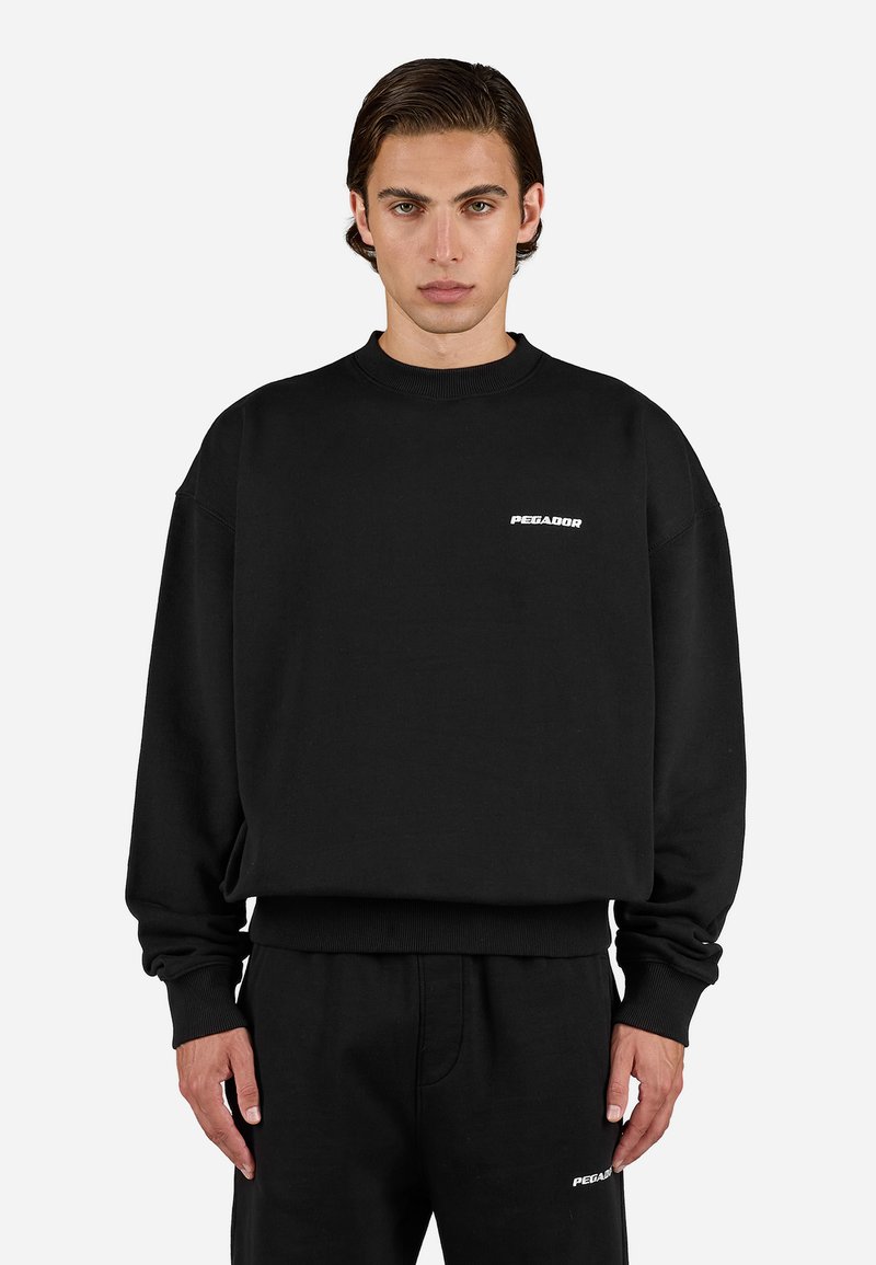 Sort sweatshirt med rund halsudskæring, lange ærmer og ribbede manchetter. Har et lille hvidt "PEGADOR" logo på brystet.