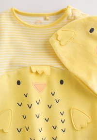 Conjunto amarillo para bebé con diseño de cara de pollito, sección superior a rayas, detalles de tela en forma de alas y gorro a juego con ojos bordados.