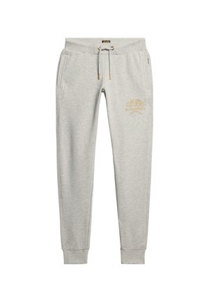 Helle graue Jogginghose mit einem Kordelzugbund, seitlichen Taschen und einem goldenen gestickten Logo am linken Oberschenkel. Weiches Material, schmal zulaufendes Bein.
