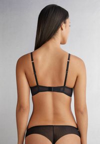 Zwarte lingerieset met een doorschijnende mesh bh met verstelbare bandjes, een haak- en oogsluiting aan de achterkant en bijpassende doorschijnende slipjes.