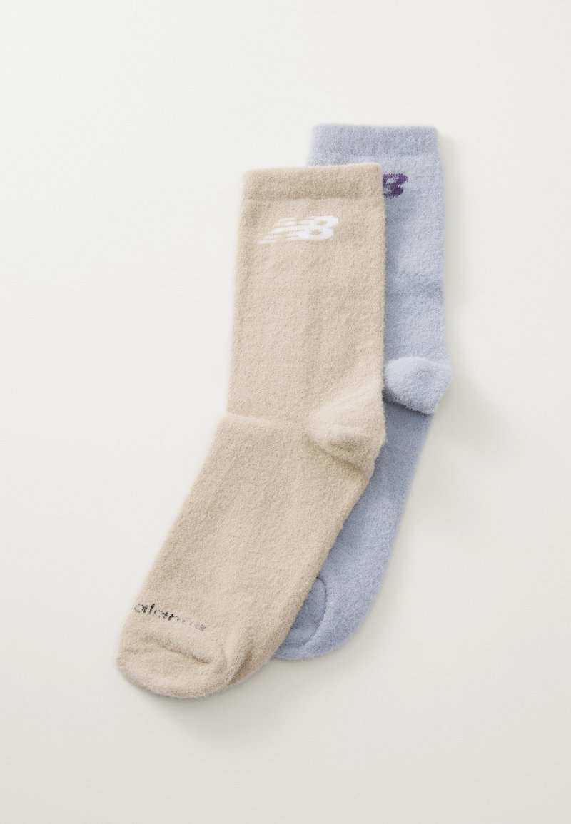 Ett par ankelsockor i beige och ljusblått. Tillverkade av mjukt, texturerat tyg. Varje strumpa har en logga i kontrasterande färg.